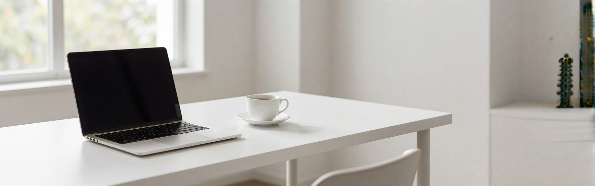 Modern minimalist office desk with laptop and coffee in soft natural light